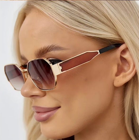 Model wearing Luna women’s retro geometric sunglasses in Gold frame with Brown Gradient lenses, in front of white wall, face turned left and looking left, hands not visible