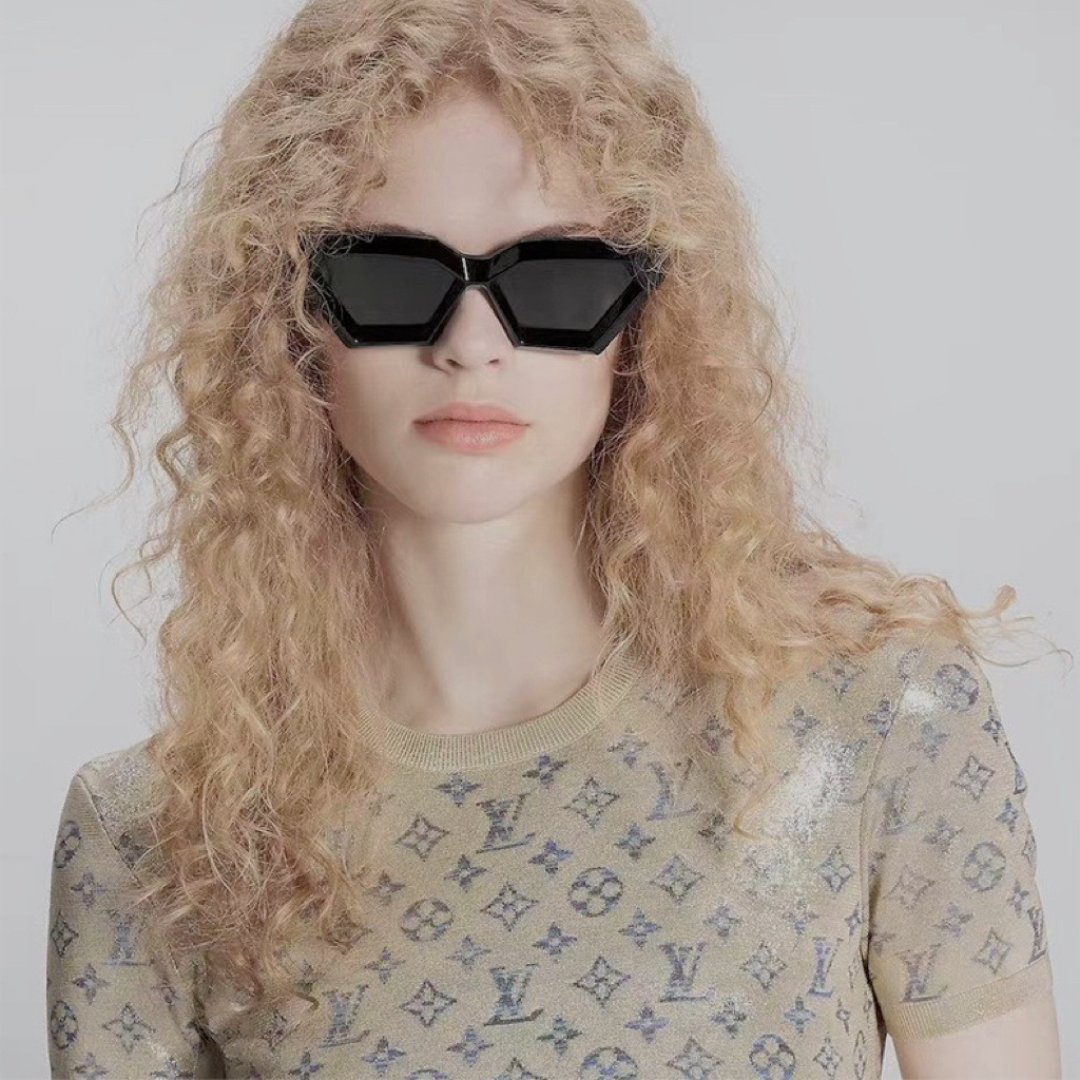 Woman wearing Paris futuristic geometric shades in Black acetate frame with Black TAC lenses, 100% UV protection, facing camera with head straight, hands not visible, white wall background.