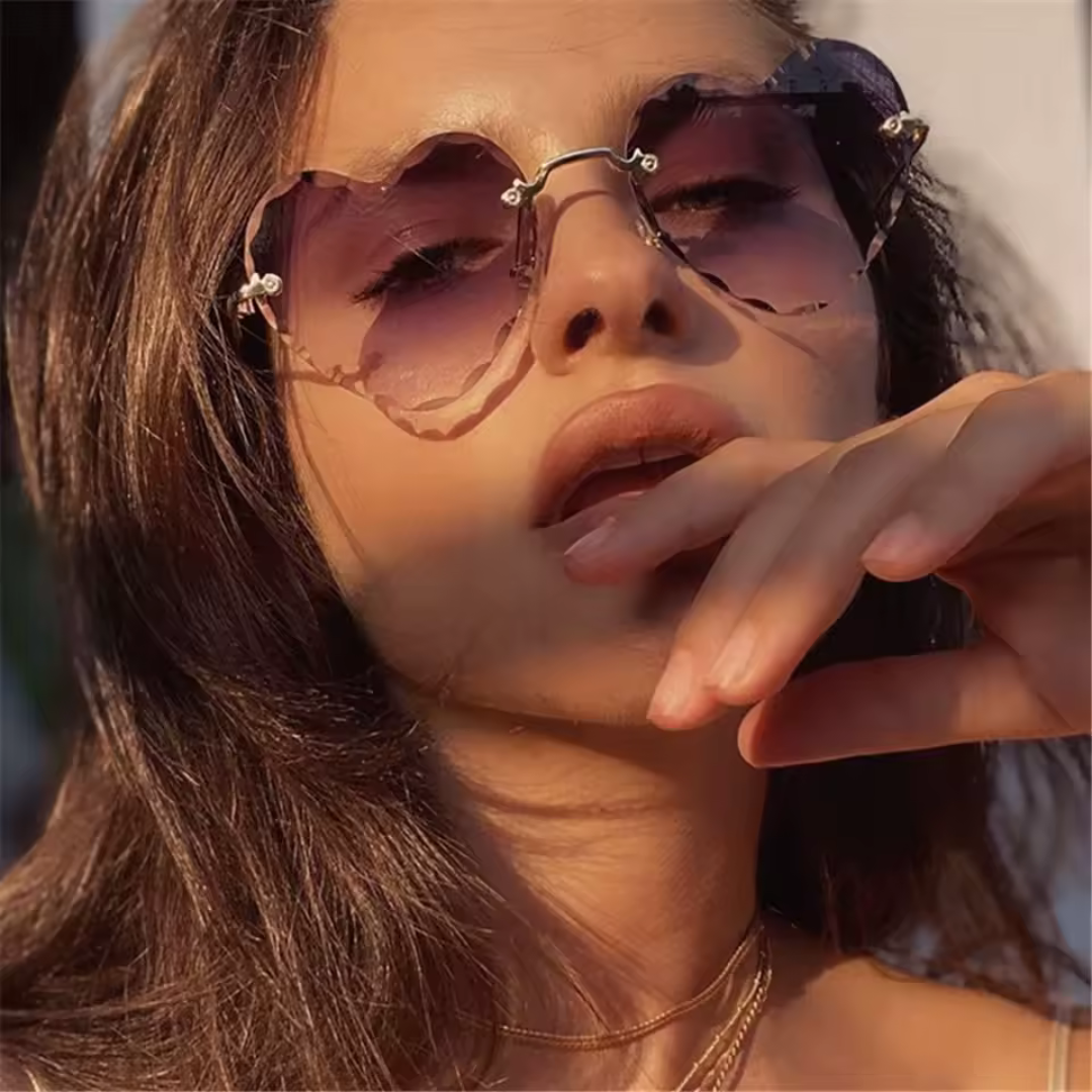 Female model wearing Élan sunglasses in Tortoise frame with Brown Gradient lenses, outdoor background, looking straight at the camera with right hand fingers softly touching her lips