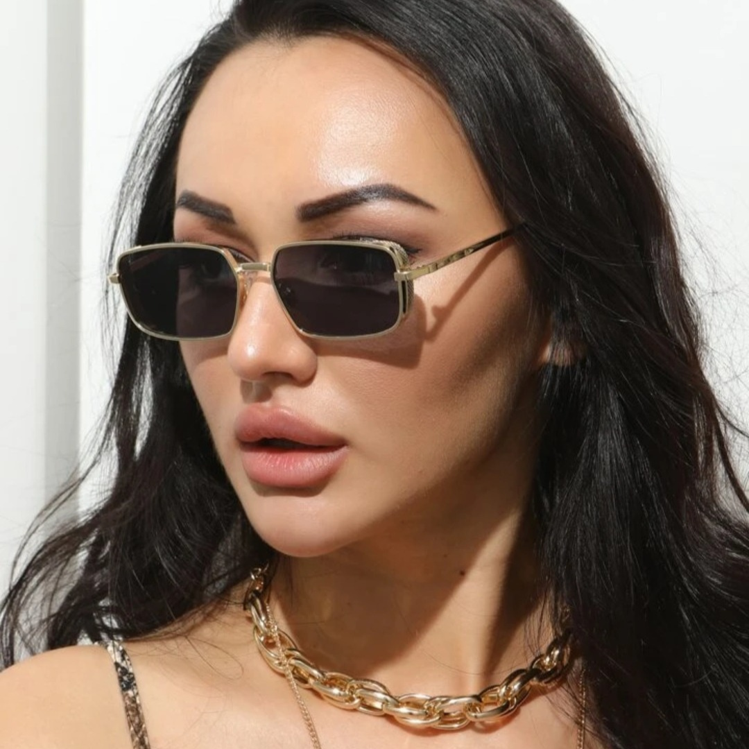 Woman wearing Nuvée rectangular sunglasses in Gold frame with black lenses, white wall background, looking slightly to the left