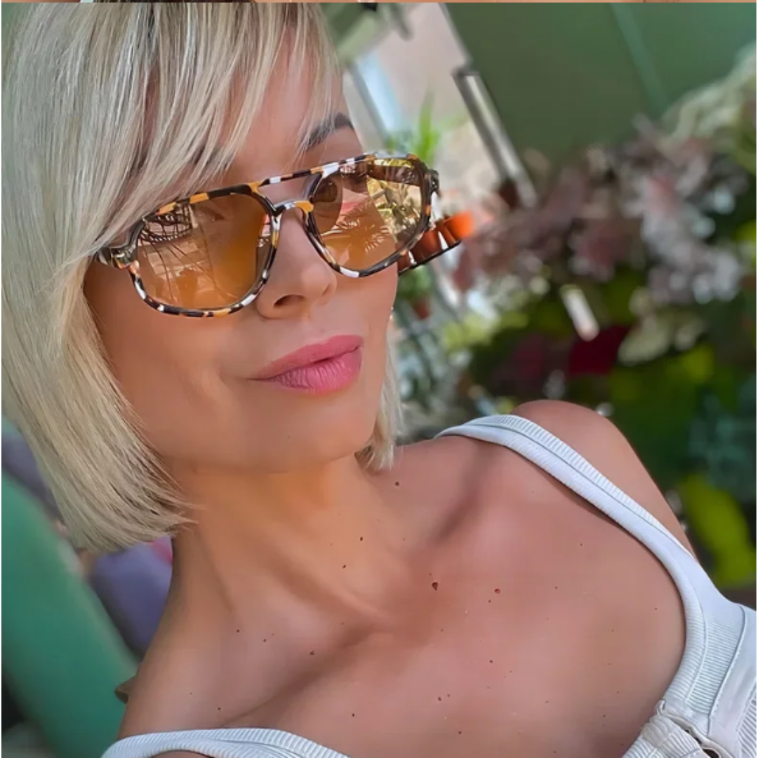 Woman wearing Brigitte aviator shades in tortoise polycarbonate frame with amber acrylic lenses, 100% UV protection, outdoor setting, face turned slightly right looking at the camera
