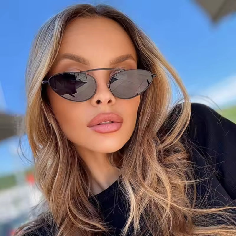 Olyra aviator women's sunglasses in black metal frame with black polycarbonate lenses, 100% UV protection, worn by female model outdoors, facing camera with slight smile expression, hands not visible