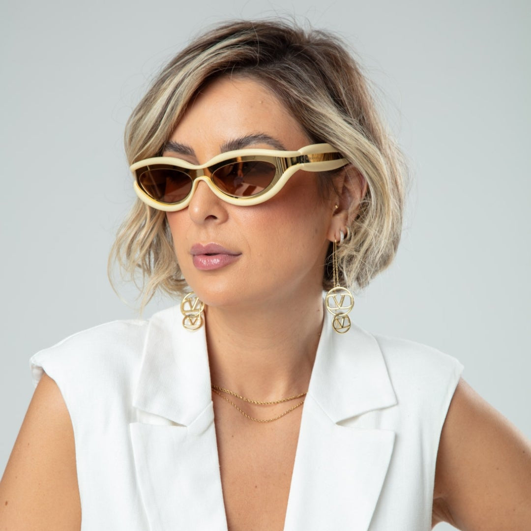 Isla women’s oval shades in Beige frame with Black lenses, worn by model against white wall — model facing slightly left, looking slightly left, hands not visible — acetate frame, TAC lenses, 100% UV protection